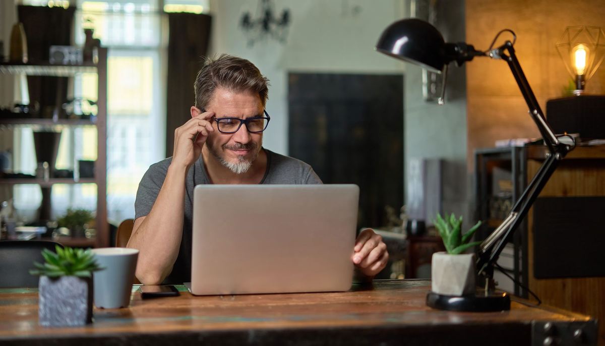 A person working on a laptop at a desk at home